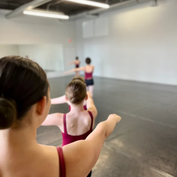 Ballet students practicing arm positions in a line during class at Ark Dance Academy