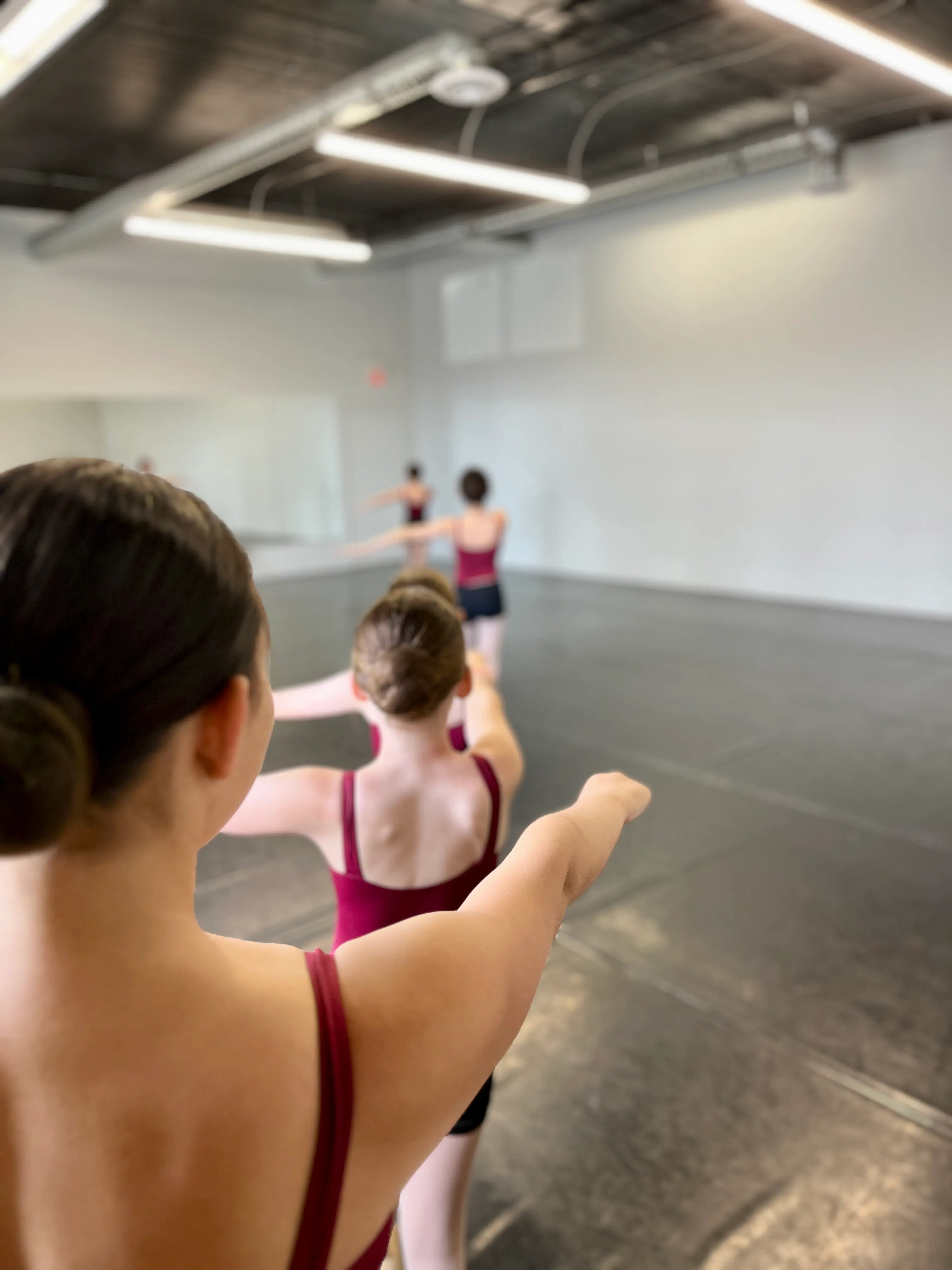 Ballet students practicing arm positions in a line during class at Ark Dance Academy